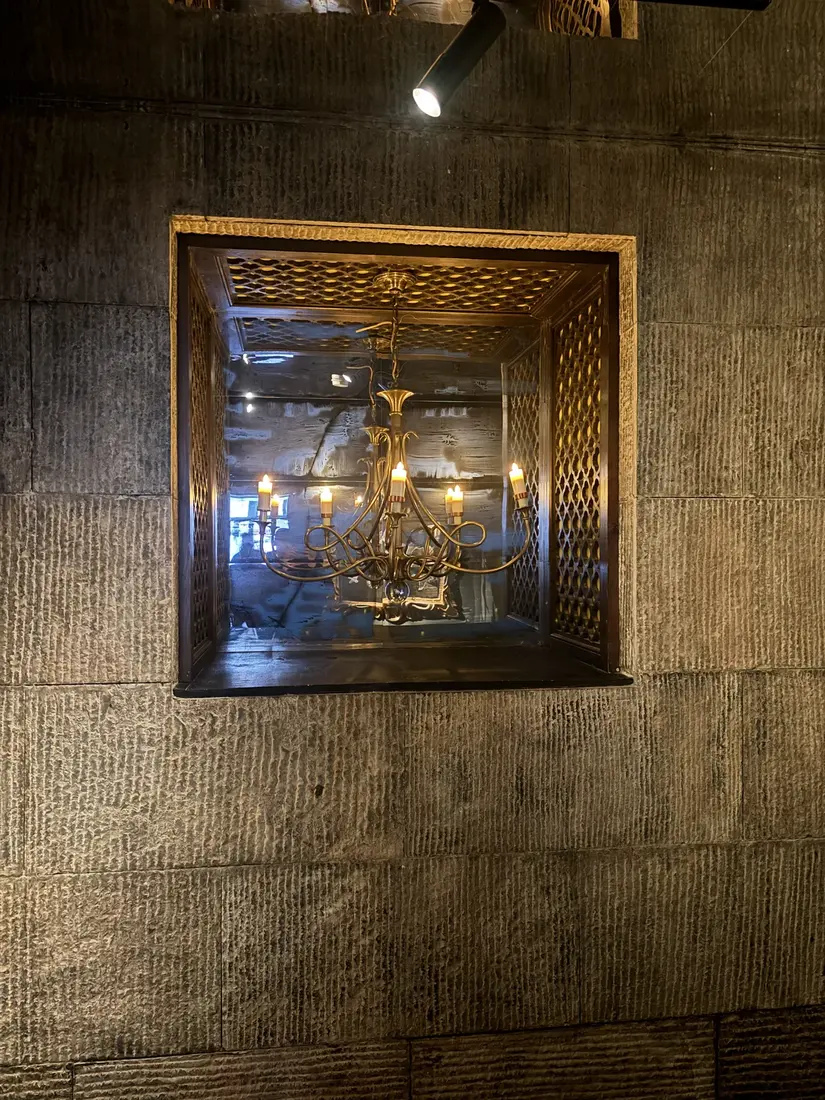 A crystal chandelier and antique gilt mirror in GUSI's passage between floors — Greenwich Village, NYC